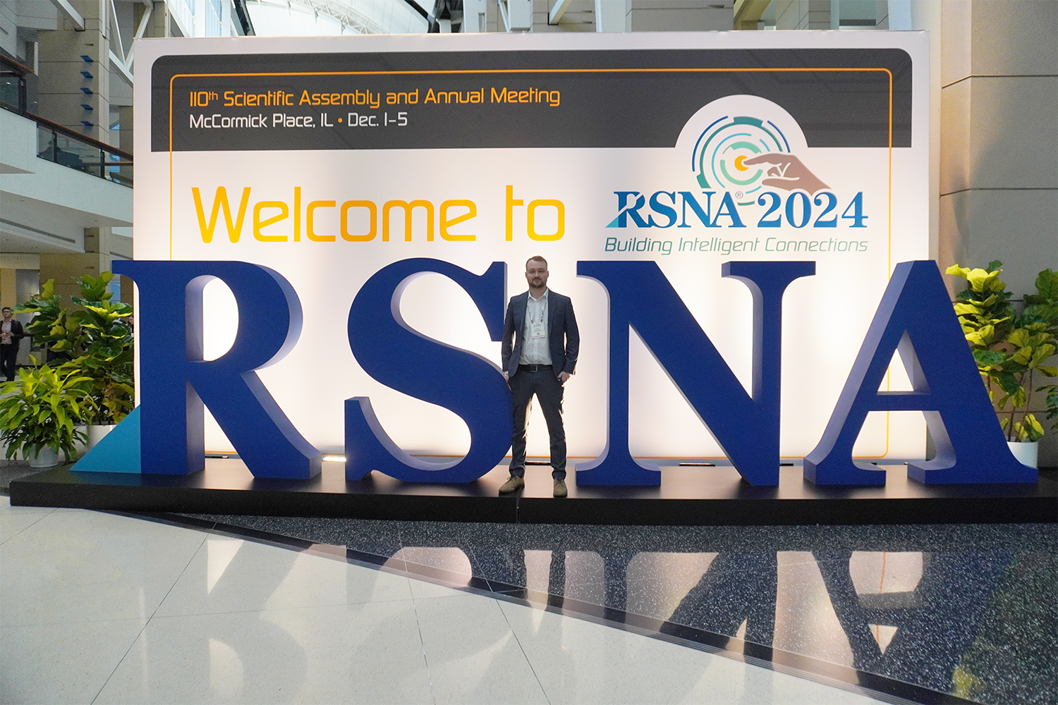 Billy Williams standing in a suit in the middle of a large RSNA sign in the conference center